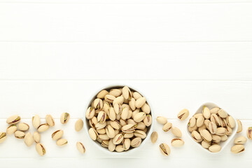 Pistachios in bowls on white wooden table