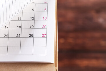 Paper calendar page on brown wooden background
