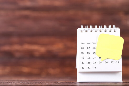 Calendar page with speech bubble on brown wooden background