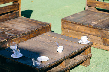 White coffee cups served on an outdoor wooden furniture terrace close up still