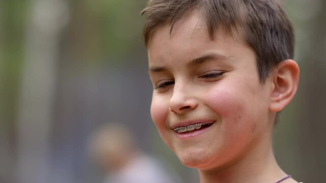 Portrait of teen boy in braces smiling to camera outdoors in forest.