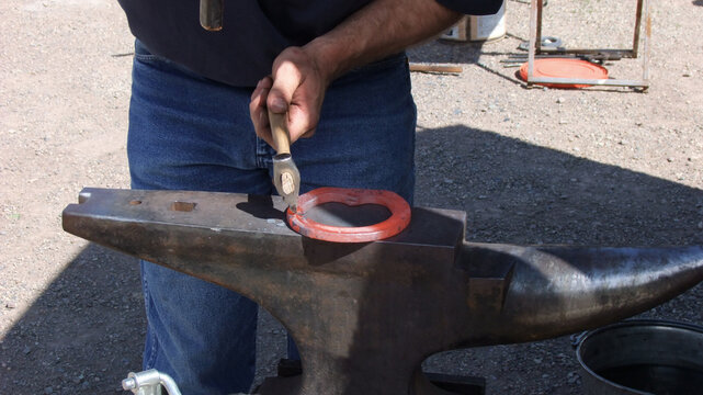Red hot horseshoe in farrier's clamp, ready for shaping.