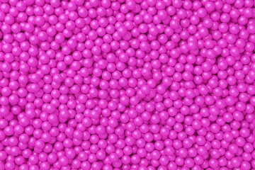 Ball pool or pit filled with pink plastic balls, abstract texture background top view flat lay from above