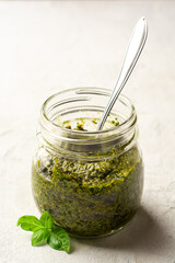 Homemade pesto sauce in glass jar on concrete background