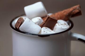 Close-up of a mug of hot chocolate with marshmallows and cinnamon.