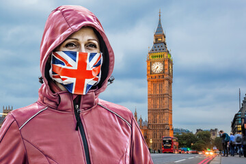 Woman wearing protection face mask with British flag against coronavirus in front of the Big Ben,...