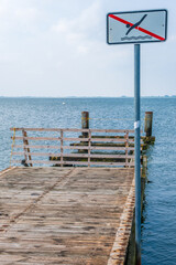 Fototapeta premium A wooden pier on the North Sea coast with a sign bathing is prohibited