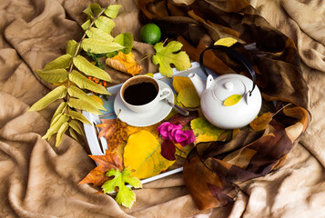 Coffee in white cup and autumn leaves close-up