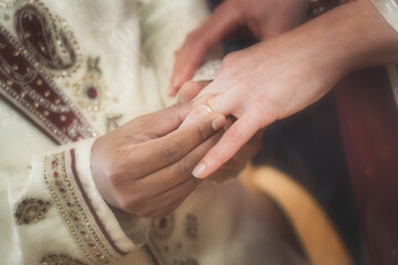 Obraz na płótnie Canvas Indian groom putting ring on a brides hand