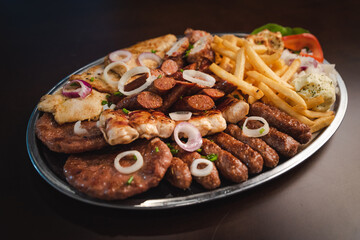 several types of roasted meat served on an oval, Serbian dish 