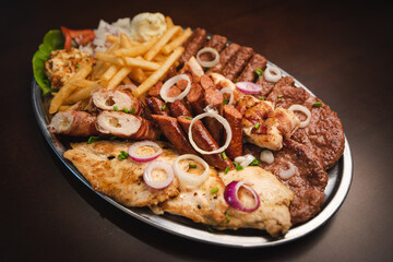 several types of roasted meat served on an oval, Serbian dish 