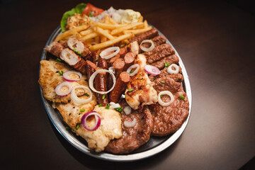 several types of roasted meat served on an oval, Serbian dish 