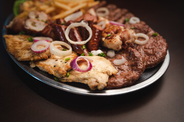 several types of roasted meat served on an oval, Serbian dish 