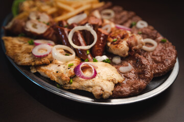 several types of roasted meat served on an oval, Serbian dish 