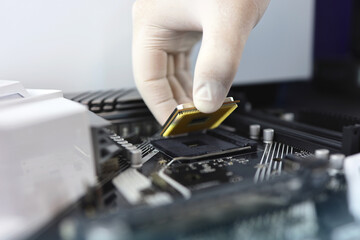 Technician plug in CPU microprocessor to motherboard socket. Workshop background