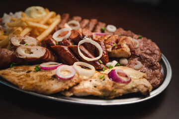 several types of roasted meat served on an oval, Serbian dish 
