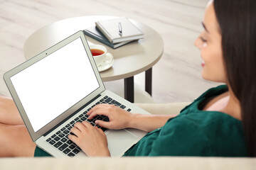 Young woman working on laptop in living room, focus on hands. Home office concept