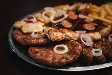 several types of roasted meat served on an oval, Serbian dish 