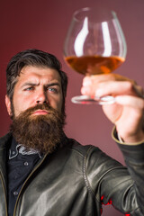 Whiskey. Brandy. Strong alcohol. Brutal man drinks whiskey. Degustation and tasting. Man in leather jacket drinks whiskey. Sommelier degustates whiskey.