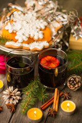 Two glasses of mulled wine with cinnamon and anise on a wooden background with fir branches and candles. Winter Christmas still life, beautiful bokeh, postcard.