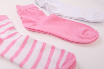 Three socks in pink color gamma, laying from white to pink close up on white background