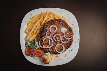 baked barbecue with french fries and salad and onion on a plate, Serbian dish 