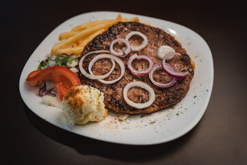 baked barbecue with french fries and salad and onion on a plate, Serbian dish 