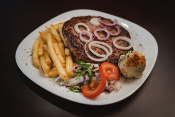 baked barbecue with french fries and salad and onion on a plate, Serbian dish 
