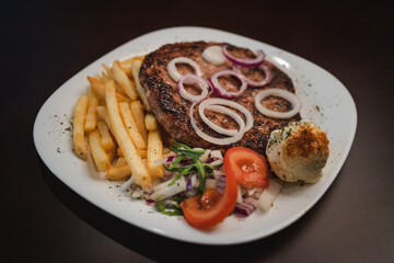 baked barbecue with french fries and salad and onion on a plate, Serbian dish 