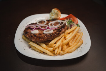 baked barbecue with french fries and salad and onion on a plate, Serbian dish 