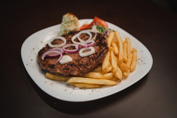 baked barbecue with french fries and salad and onion on a plate, Serbian dish 