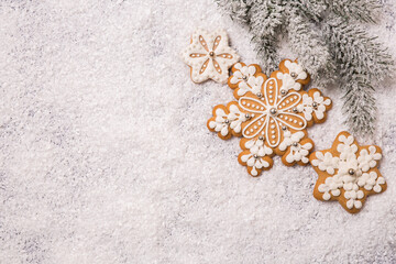 Christmas background, spruce branch with gingerbread cookies on a white snowy background. View from above. Idea, holiday concept.