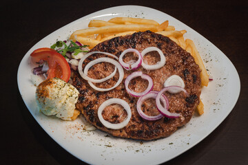 baked barbecue with french fries and salad and onion on a plate, Serbian dish 