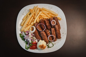 peceni rostilj sa pomfitom i salatom na tanjiru, srpsko jelo 