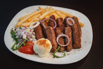 peceni rostilj sa pomfitom i salatom na tanjiru, srpsko jelo 