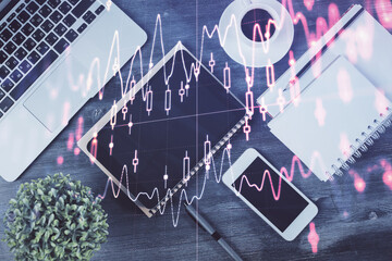 Fototapeta premium Double exposure of forex chart hologram over desktop with phone. Top view. Mobile trade platform concept.