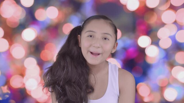 ni&ntilde;a bonita y divertida haciendo caras, sonriendo en un fondo desenfocado de luces