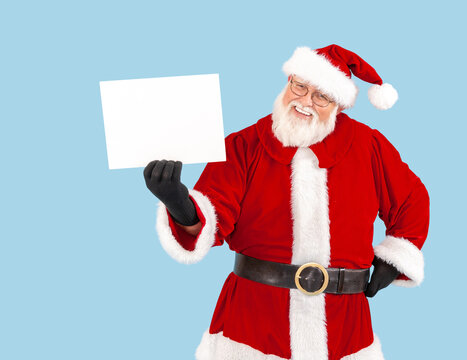 A happy Santa Claus on a blue background. holding up a blank sign.