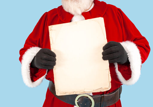 A happy Santa Claus on a snowy background. is holding up a blank parchment paper for your naughty or nice list..