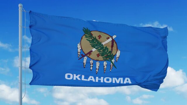 Oklahoma flag on a flagpole waving in the wind, blue sky background. 4K