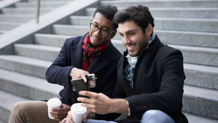 Business guys following the financial markets on their smartphone while drinking american coffee