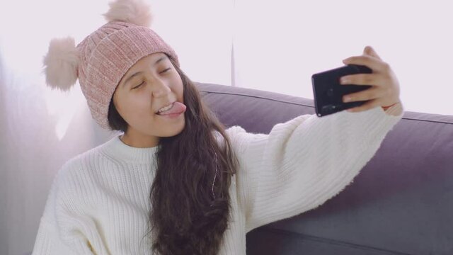 niña bonita haciendo caras tomándose fotos selfis con su celular feliz en casa 