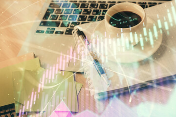 Double exposure of forex chart drawing and desktop with coffee and items on table background. Concept of financial market trading