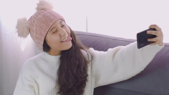 ni&ntilde;a bonita con ropa de invierno, feliz  tom&aacute;ndose fotos con su celular en la comodidad de su hogar 