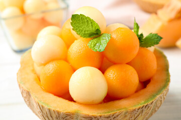 Different melon balls with mint on white table, closeup