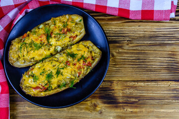 Plate with baked stuffed eggplants on a wooden table. Top view
