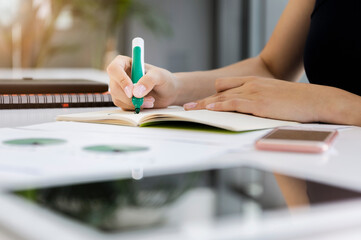 Close-up of businesswoman writing on book at desk in office