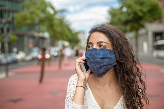 Close-up of young woman wearing mask talking over mobile phone in city