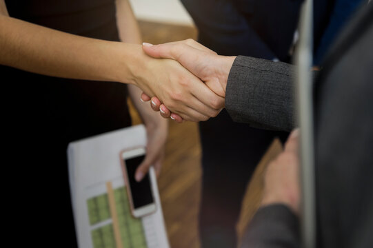 Close-up of colleagues giving handshake in office