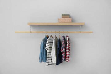 Rack with different clothes on light background